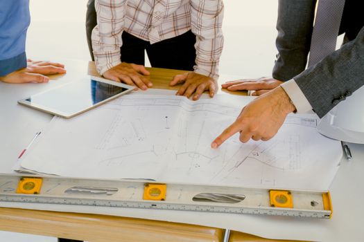 Team of engineers discussing architecture plan sketch at the construction site.