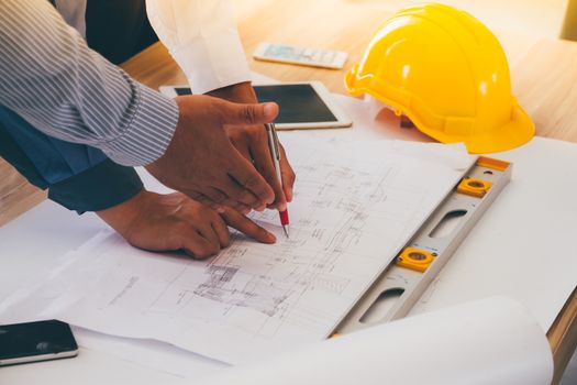 Team of engineers discussing architecture plan sketch at the construction site.