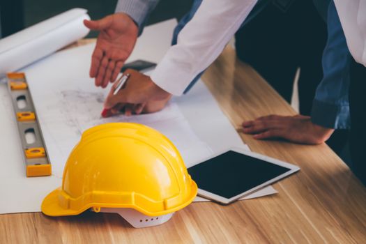 Team of engineers discussing architecture plan sketch at the construction site. Selective focus