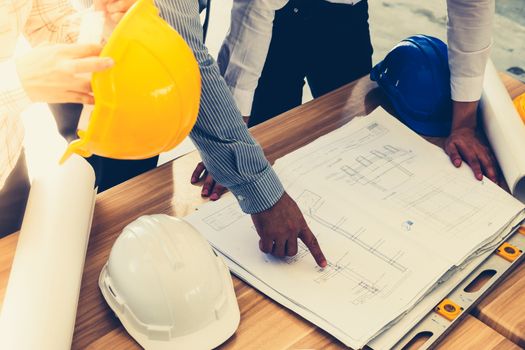 Team of engineers discussing architecture plan sketch at the construction site. Vintage tone