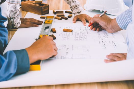 Team of engineers discussing architecture plan sketch at the construction site.