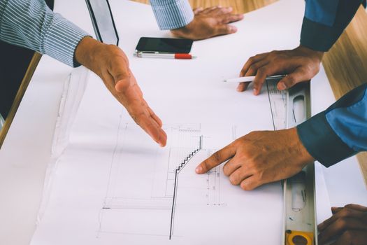 Team of engineers discussing architecture plan sketch at the construction site.