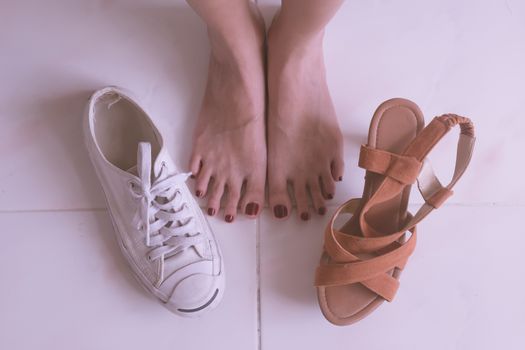 Close up of female feet with high heels shoes and casual sports shoes.