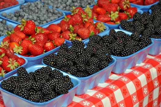 Table full of strawberries, blueberries and blackberries at market