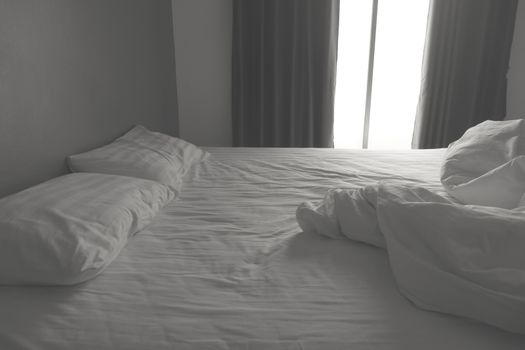 Messy white bedding sheets and pillows. black and white tone