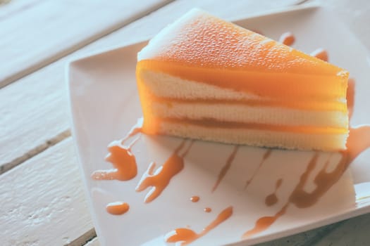 Orange cake in white dish on the wood table.