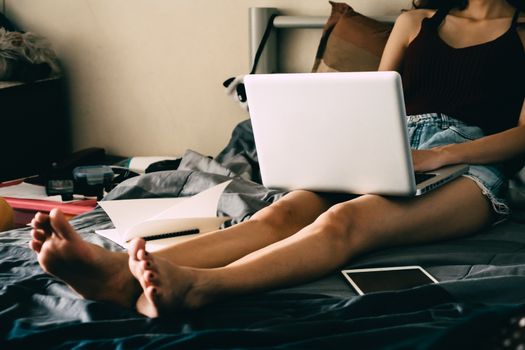 Close up of young woman using laptop while sitting on her bed,  Films grain filter.