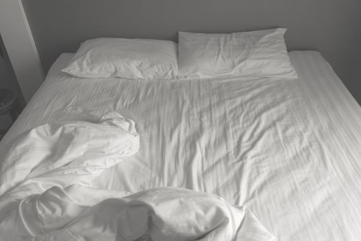 Messy white bedding sheets and pillows. black and white tone
