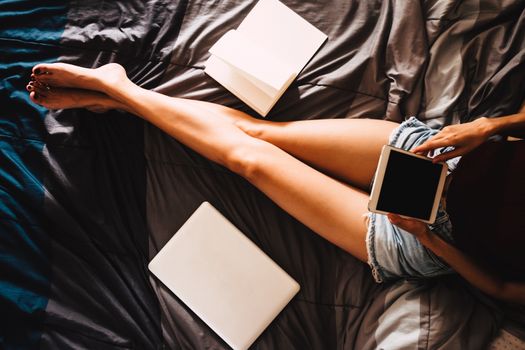 Close up of young woman using tablet while sitting on her bed,  Films grain filter.