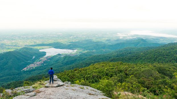 Young man enjoying a valley view from top of a mountain.