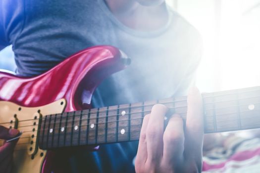 Close up of Male hands playing electric guitar, Flare from the sunlight, Selective focus