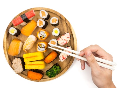 Top view of Sushi set on wooden plate and hand holding chopsticks on white background, Japanese food.