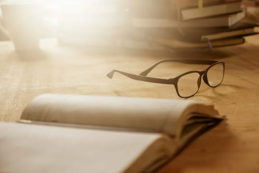Close up of eyeglasses with books on wooden desk, Selective focus,  Flare sun light,Vintage tone.
