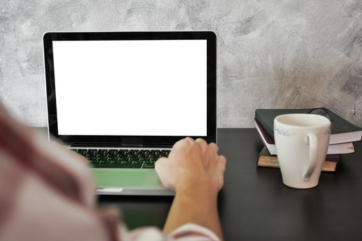 Close up of male hands using laptop with white screen monitor on the desk.