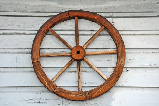 Old weathered wagon wheel on white wall