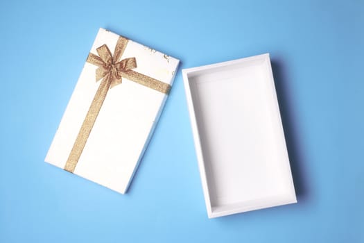 Top view of open white gift box on blue background.