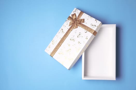 Top view of open white gift box on blue background. Free space for text