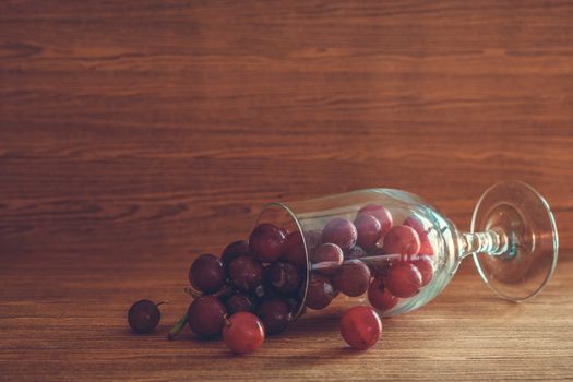 Red grapes in glass on the wooden table. Free space for text
