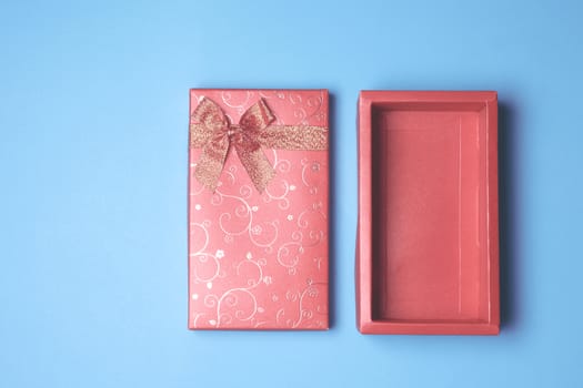 Top view of open red gift box on blue background. Free space for text
