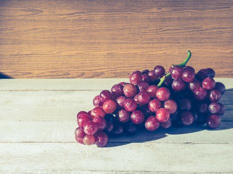 Red grapes on the wooden table. Free space for text