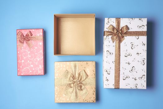 Top view of open gift box and presents on blue background.