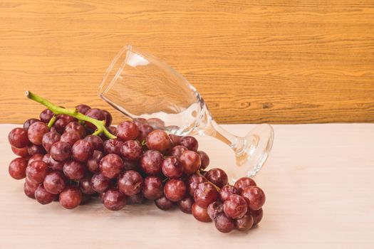 Red grapes with wine glass on the wooden table. Free space for text