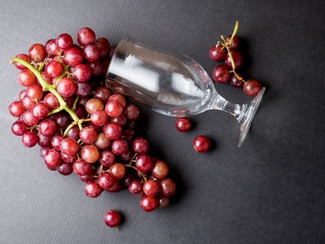 Top view of Red grapes with glass on a black background.