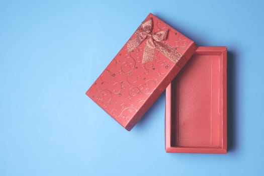 Top view of open red gift box on blue background. Free space for text