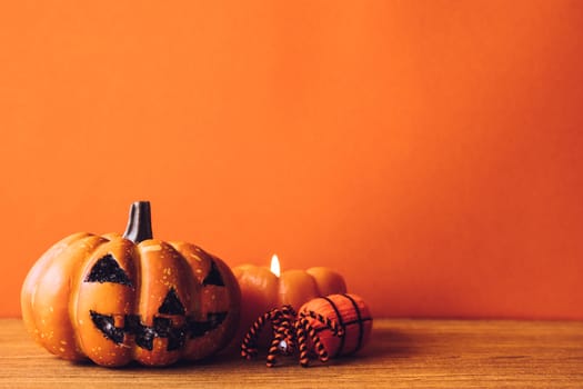 Halloween pumpkins with candlelight on an orange color background. Free space for text