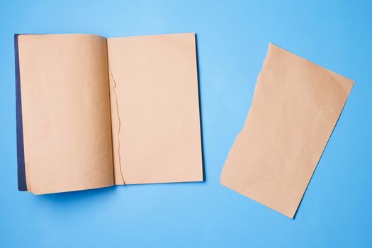 Blank notebook with a piece of note paper on blue background.