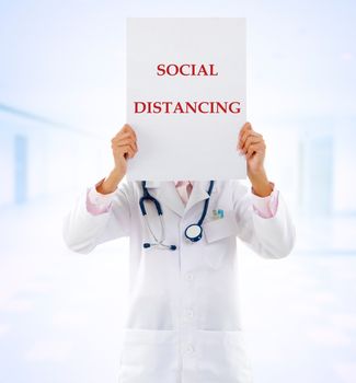 Medical doctor holding a card with social distancing on it.