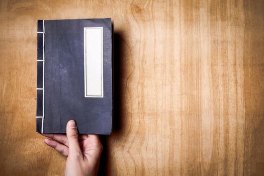 Top view of hands holding a book on wood background. Free space for text