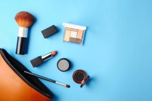Top view of cosmetics set for makeup on a blue background. Free space for text.