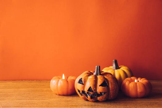 Halloween pumpkins with candlelight on an orange color background. Free space for text