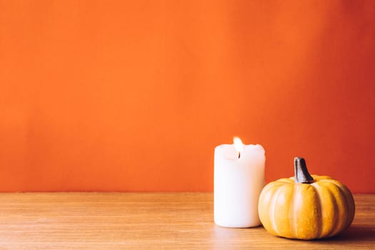 Pumpkin with candlelight on an orange color background. Free space for text