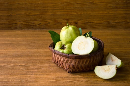 Fresh guava fruit in basket on wooden table background.