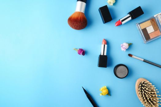 Top view of cosmetics set for makeup on a blue background. Free space for text.