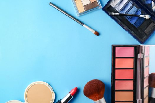 Top view of cosmetics set for makeup on a blue background. Free space for text.
