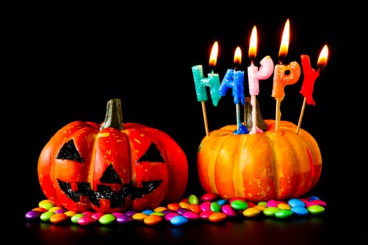 Halloween pumpkin with candies and candlelight on a black background.