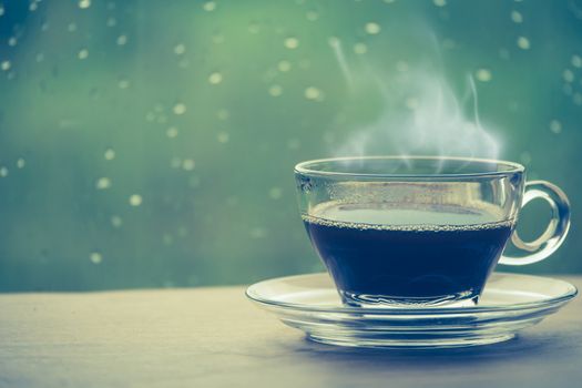Cup of coffee on the table inside the window, coffee break in the morning with rainy day, relaxing and refreshing concepts.