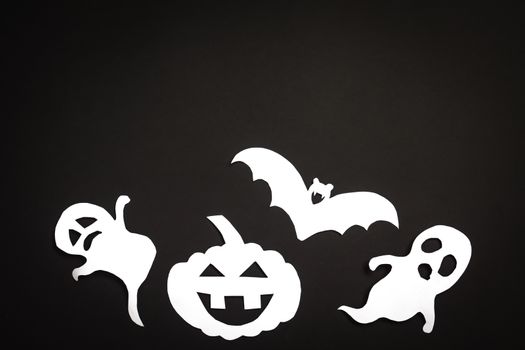 Halloween holiday background with pumpkin, ghosts and bat cut paper on black background. Free space for text.