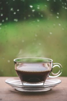 Cup of coffee on the table inside the window, coffee break in the morning with rainy day, relaxing and refreshing concepts.