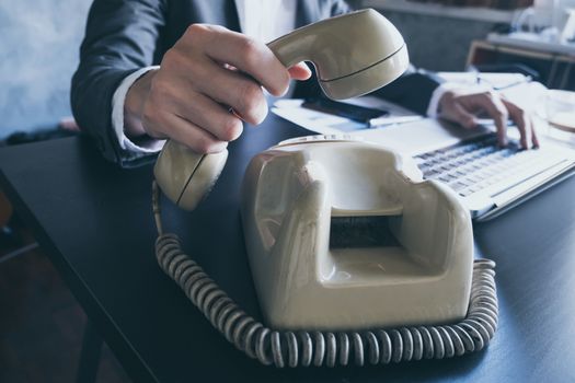 Close up of businessman using telephone while working on the office desk.
