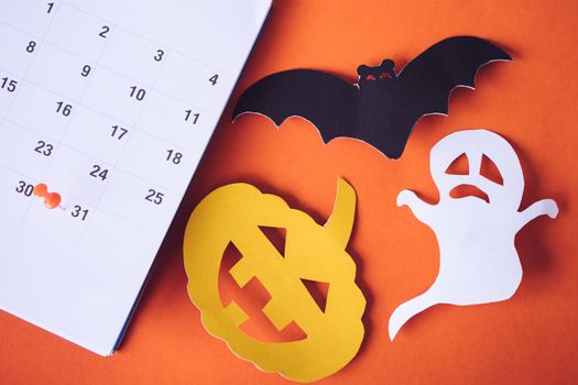Halloween holiday concept, Pin on calendar event planning, pumpkin, ghost and bat cut paper on orange background.