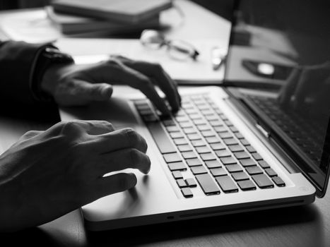 Close up of businessman using laptop on the office desk. Black and White tone