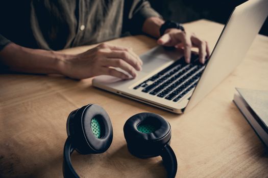 Close up of casual man using laptop on the desk at home.