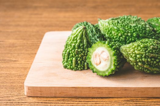 Bitter melon or bitter gourd on wooden tray. Free space for text