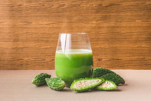 Herbal juice with bitter melon or bitter gourd on wooden background.