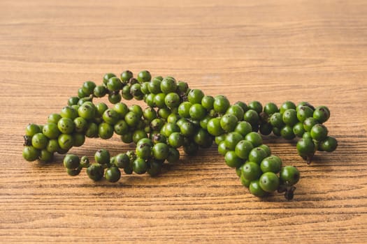 Green peppercorns on wooden background.