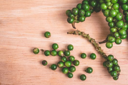 Green peppercorns on wooden background.